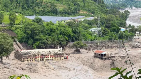 Shaktimaya  Tamang Mud and sand are piled up against a hydropower plant affected by a flash flood in northern Nepal