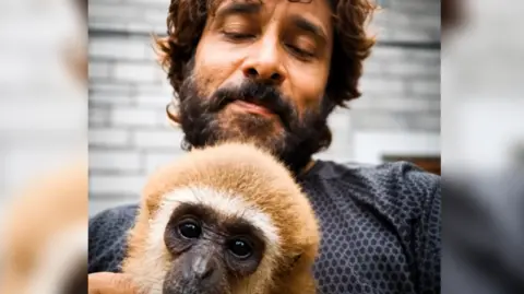 Vikram/Instagram Vikram, an actor from Tamil Nadu, poses with a lar gibbon in a now-deleted video