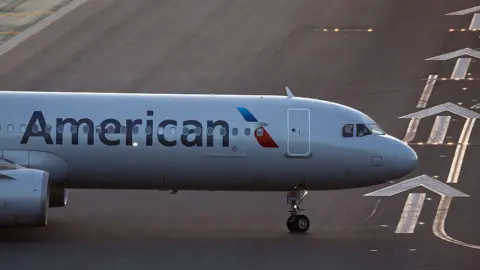 Kevin Carter/Getty Images The front of an air plane with the American logo on a runway. 
