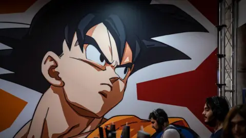 Getty Images A graphic from the Dragon Ball Z comic is seen displayed on a wall above several people on computers
