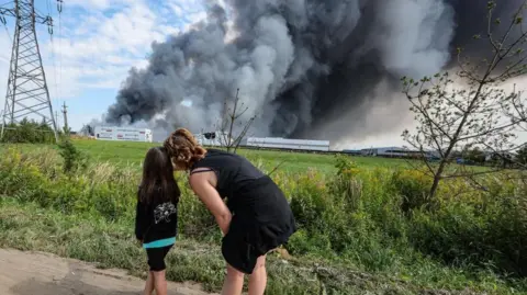 EPA People watch as smoke rises above a Wildberries facility following a reported Ukrainian drone strike at the Koledino Industrial Park near Podolsk in Russia on 16 August.