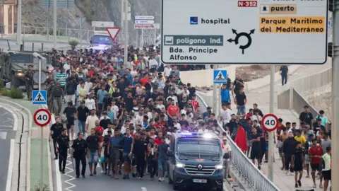 Reuters Police officers and Spanish soldiers escort a big group of migrants to the border to take them out of Spain,