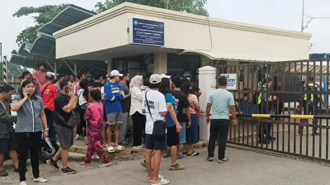 Reuters People crowd outside the gate of the Ateneo de Zamboanga junior high school where a shooting left two students dead