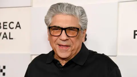 Getty Images Vincent Pastore wears a black polo shirt and black-rimmed glasses.