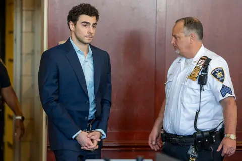 Getty Images Luigi Mangione appears in a courtroom wearing handcuffs