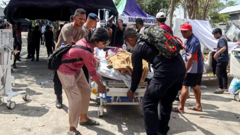 Reuters Police officers help move a patient to an open-area shelter at a hospital, following an earthquake felt in Labuan Bajo, East Nusa Tenggara province