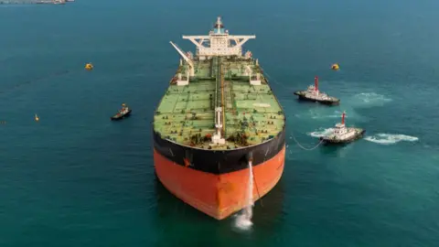 Getty Images Stock image of an oil tanker pictured front on, with several tugs surrounding the ship