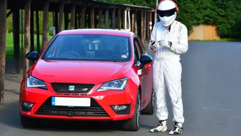 BBC The Stig by a red car