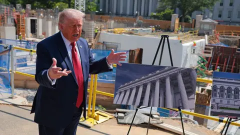 Getty Images President Trump showing a rendering of the ballroom in front of construction materials on 19 May. 