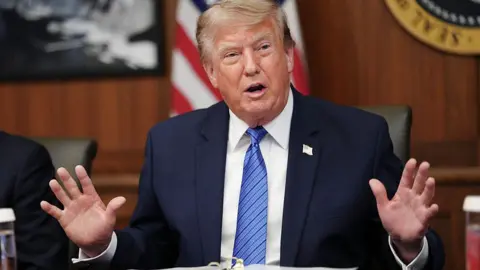 Getty Images Trump at Camp David in blue jacket and blue tie holding both hands up  