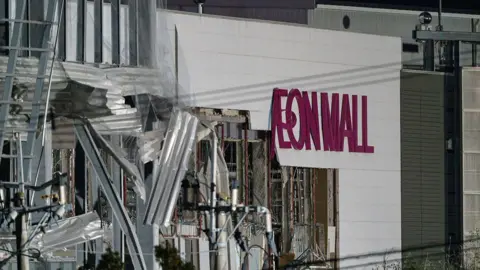 Getty Images A damaged building with the words Aeon Mall on its side
