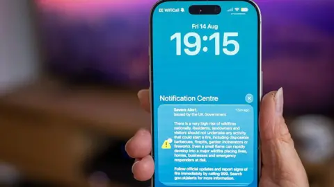 Getty Images A picture of a phone with blue background carrying the UK government Severe Alert warning of the risk of wildfires.
