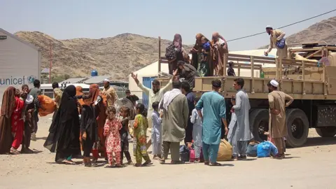 AFP via Getty Images This photograph taken on June 24, 2026 shows Afghan returnees deported from Pakistan, climbing down a militray truck upon their arrival at Omari camp near the Afghanistan-Pakistan zero point border crossing in Torkham, Nangarhar province. 