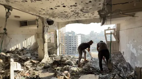 Supplied Men assess scene of Israeli strike on high-rise block in Gaza City on 2 August