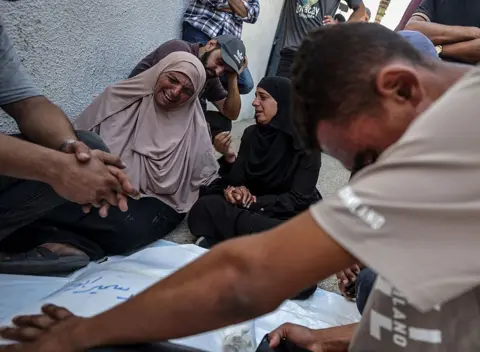 Getty Images Palestinians seen crying over bodies of people killed in an Israeli attack targeting a beachfront cafe in Gaza City