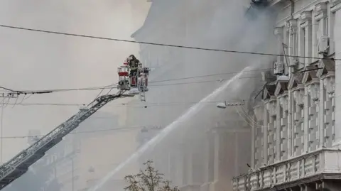 Reuters A firefighter on an extended platform helps with hosing down the building