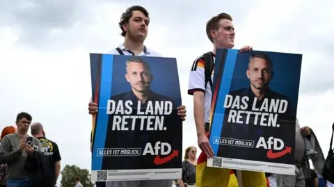 Reuters Supporters of the Alternative for Germany (AfD) party hold placards as they attend AfD top candidate Ulrich Siegmund's campaign event ahead of the upcoming Saxony-Anhalt state elections in Magdeburg, Germany