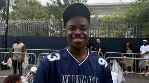 Prince Dean Sithole wears a navy jersey and baseball hat.