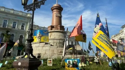 Ukrainian flags adorn a monument that has no statue
