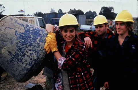 Fremantle Media/Shutterstock Natalie Imbruglia leans against a concrete mixer in a promotional photograph for the TV show Neighbours