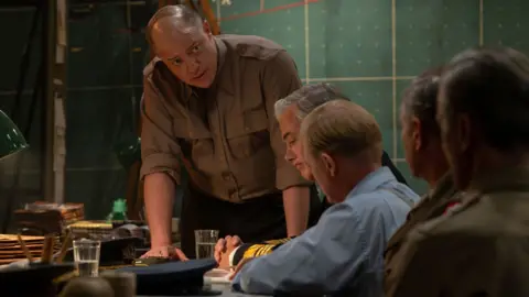 Alex Bailey/StudioCanal SAS Brendan Fraser in uniform on the set of Pressure, he is leaning on a table looking tense 