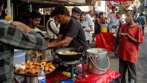 Getty Images Customers eat breakfast next to street food stalls outside Goregaon train station on April 23, 2026 in Mumbai, India.