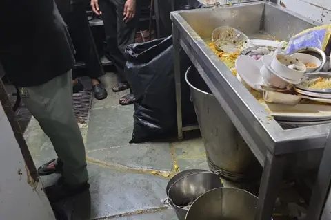 Food and Drug Administration, Maharashtra A picture of a kitchen where dirty utensils are kept in the sink and the floor also has dirty water 