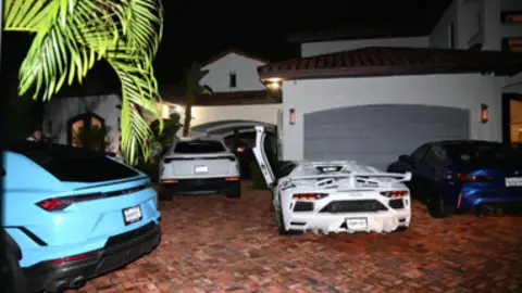 US Department of Justice Several supercars parked in the courtyard of a large villa