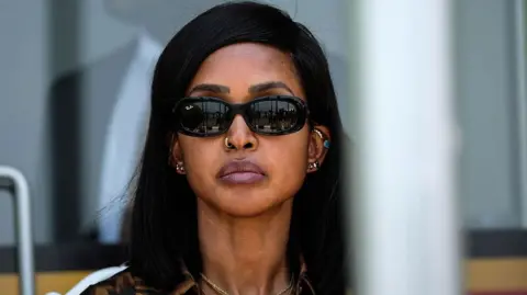 Getty Images A close-up of Princess Ruth Komuntale with straight black hair, wearing dark sunglasses and several pieces of jewellery, including earrings, a nose ring and a necklace. 