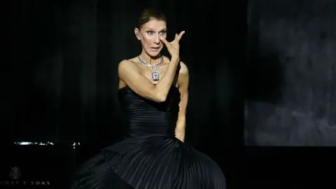 Getty Images Dion wipes away a tear on stage