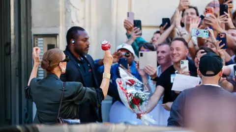 Getty Images The singer meets fans outside her hotel, with one giving her flowers