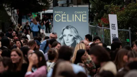 Getty Images A poster with Dion's face near a crowd in Paris