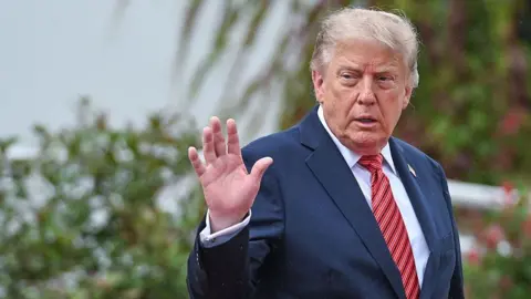 Getty Images U.S. President Donald Trump turns to wave toward gathered media while walking with Irish President Catherine Connolly during the official farewell as he leaves Aras an Uachtarain on September 12, 2026, in Dublin, Ireland. (
