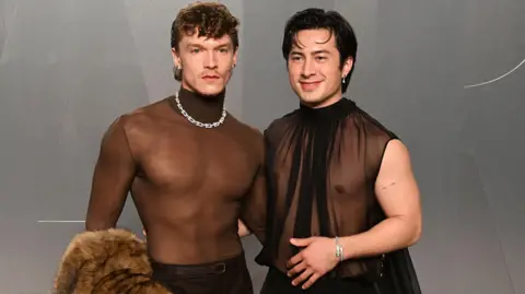 Getty Images Connor Storrie and Hudson Williams attend the 2026 Vanity Fair Oscar party in LA, they are both wearing sheer chiffon black tops.