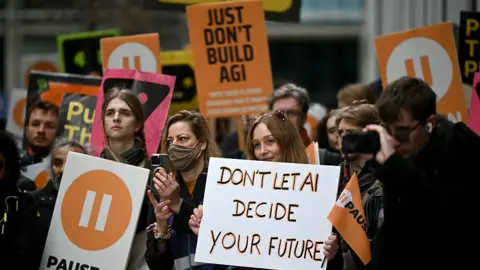 AFP via Getty Images A group of campaigners at a protest in London in February. A woman holds up a sign which reads "Don't led AI decide your future". Behind her, another sign reads "Just don't build AGI".