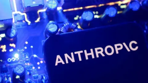 Reuters A blue  Anthropic logo on a flat surface with blue nobs and dials in the background. 