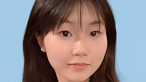 Aapple Wong Close-up of a young Chinese girl smiling at the camera, against a blue background