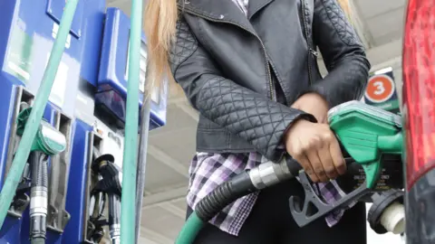 Getty Images Person wearing a black leather jacket filling up their car from the petrol pump