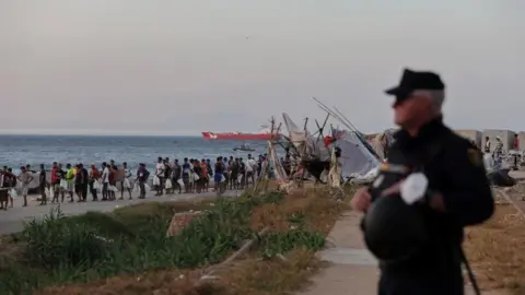 Reuters Migrants queue for a Red Cross food distribution at Trampolin beach, following recent mass crossings of migrants from Morocco to Ceuta.