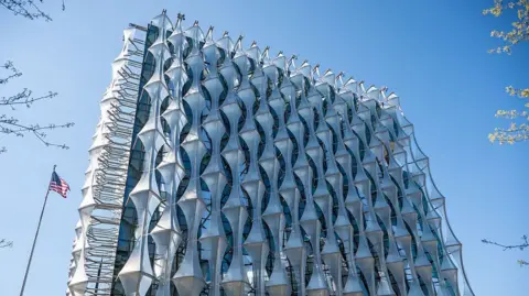Getty Images A building that looks like a silver metal cube with crystal style metal decoration covering it entirely. A US flag can be seen flying on a pole to its left.