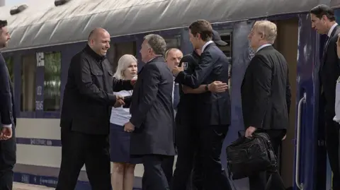 AFP via Getty Images Witkoff and Kushner step off a train and shake the hands of officials waiting for them 